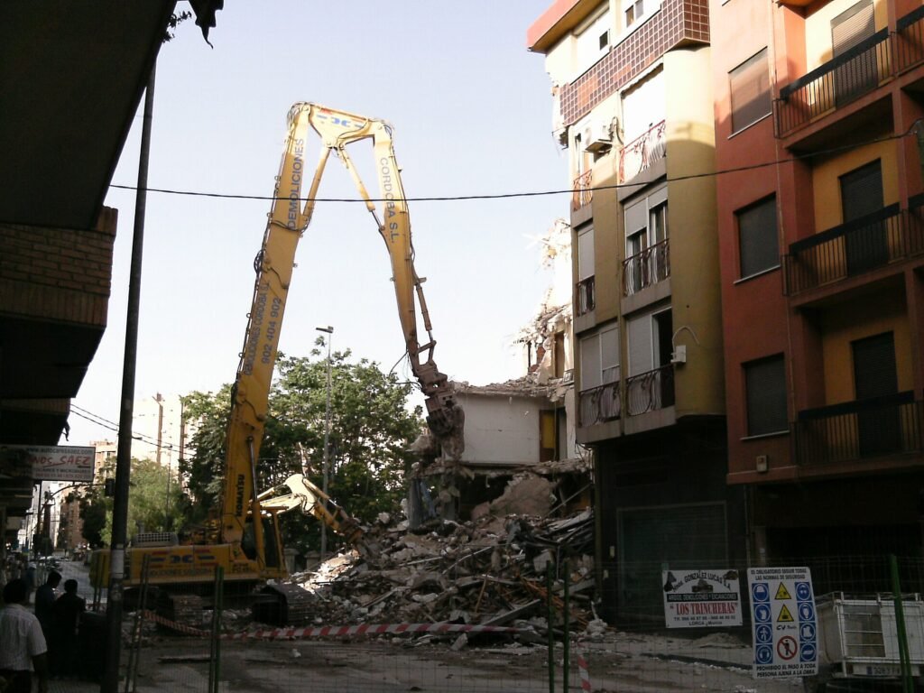 Excavadora retirando los escombros de un edificio derruido tras un terremoto