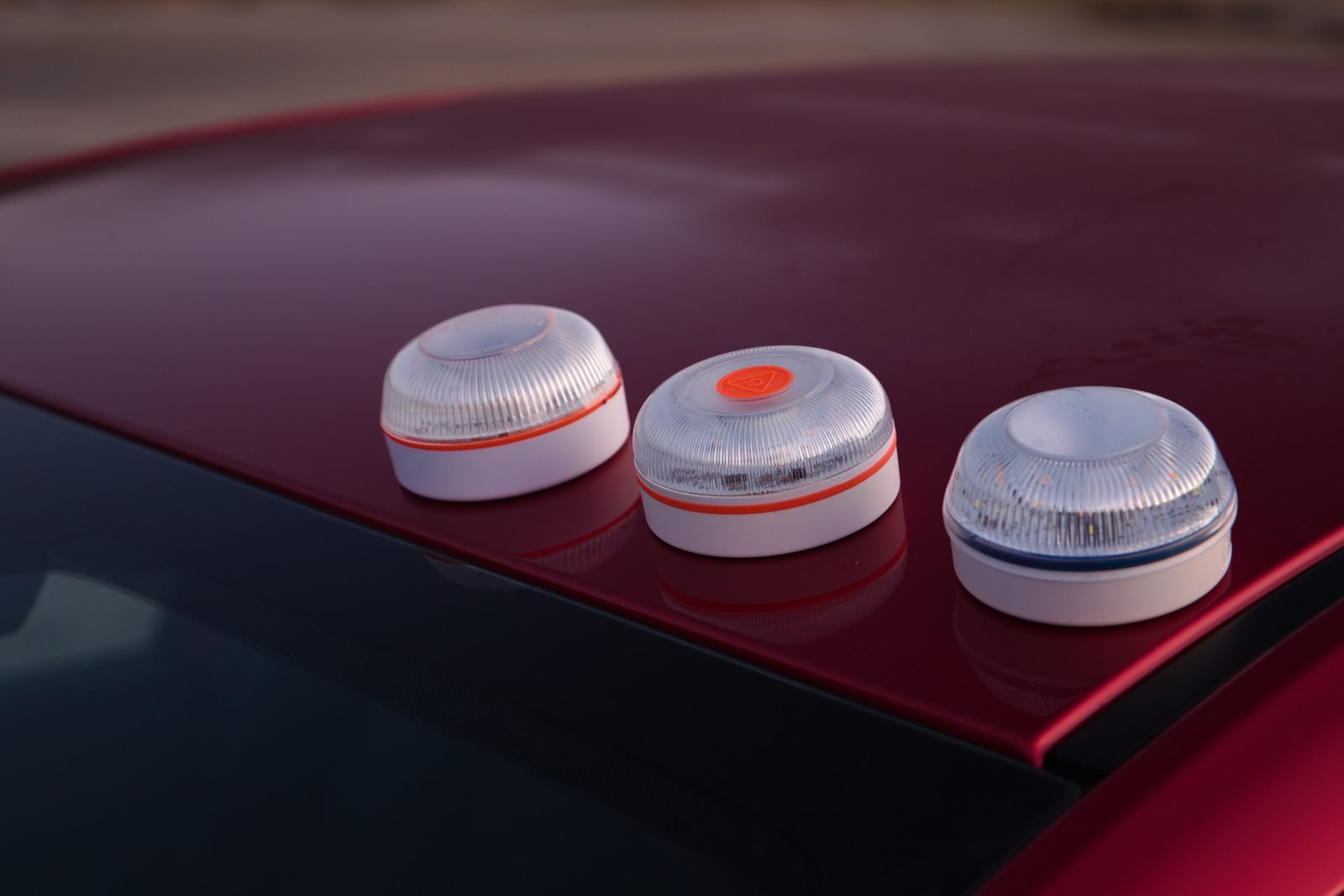 Tres balizas V16 de la marca Help Flash sobre el techo rojo de un coche