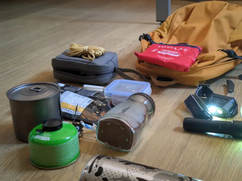 Mi equipo de casa en el suelo: hornillo, linterna frontal, manta térmica y la mochila